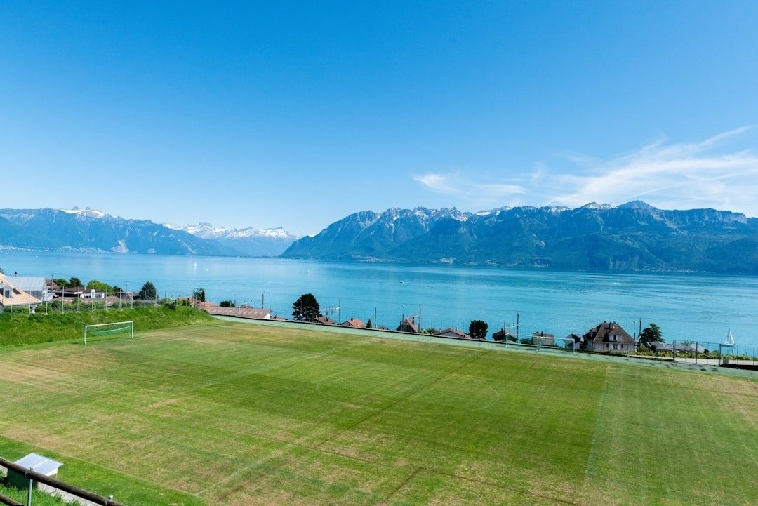 Grass football field beside Lake Geneva and the Swiss Alps