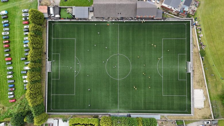Aerial view of an amateur football pitch with players and spectators