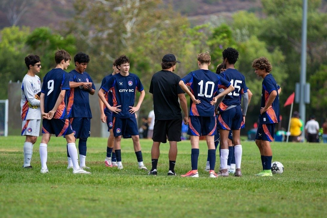 Youth soccer players gather around a coach during a matchday briefing