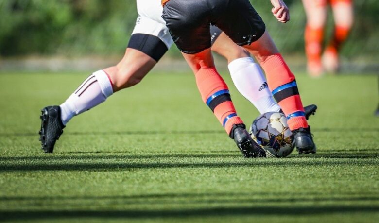 Close-up of two football players contesting the ball on grass