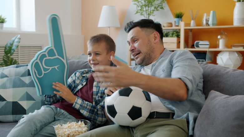 Father and son cheering during a soccer match at home