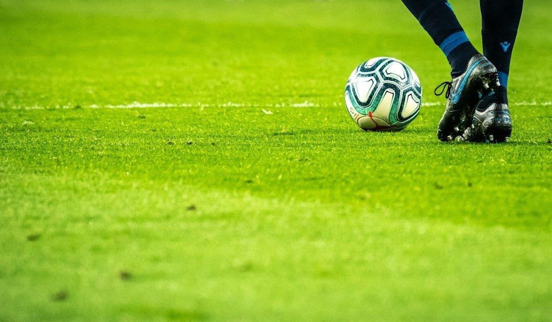 Soccer ball and cleated feet on a bright green grass field