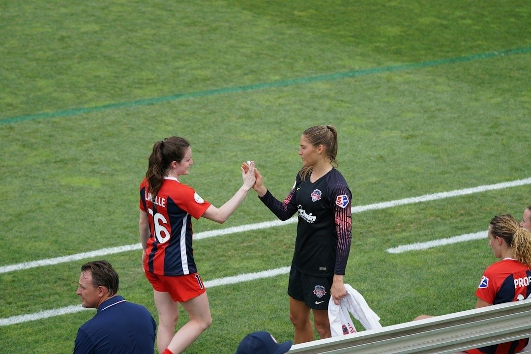Two soccer players exchange a respectful high-five beside the field